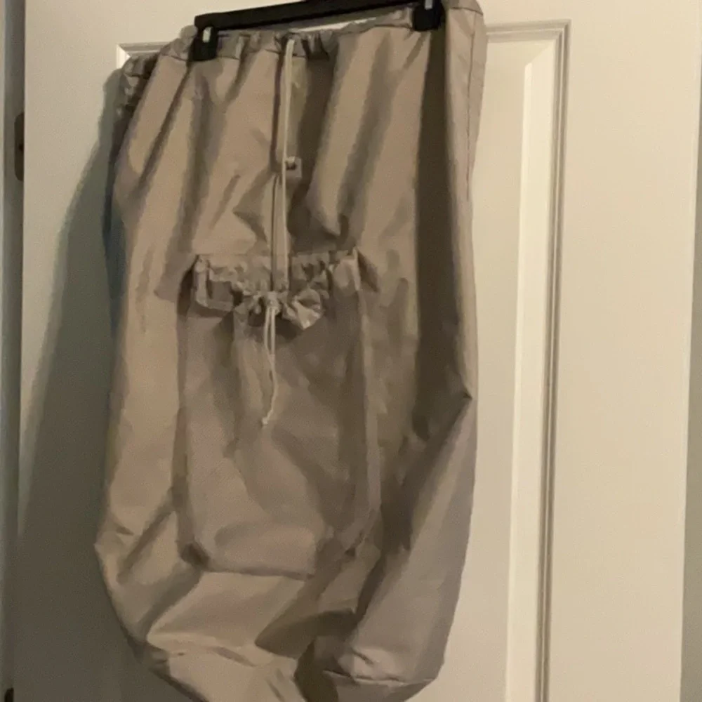 Large gray laundry bag with handle and backpack straps. Front and inside pockets